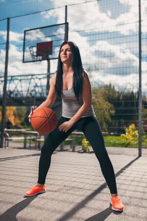Young female basketball player training outdoors on a local courtの写真素材