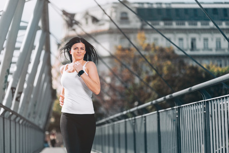 City workout. Beautiful young woman running in an urban settingの写真素材