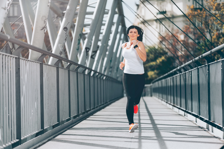 City workout. Beautiful young woman running in an urban settingの写真素材
