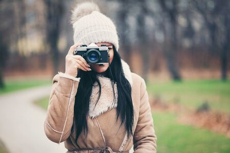 Female photographer taking pictures outdoors with an old vintage camera