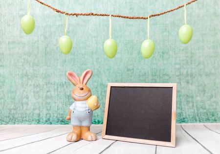 Traditional Easter holiday bunny and an empty blackboard
