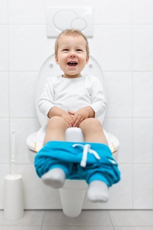 Adorable young child sitting and learning how to use the toiletの写真素材