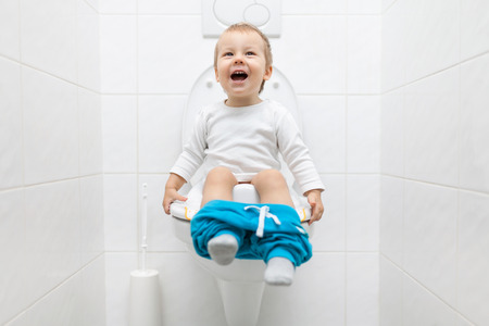 Adorable young child sitting and learning how to use the toiletの写真素材