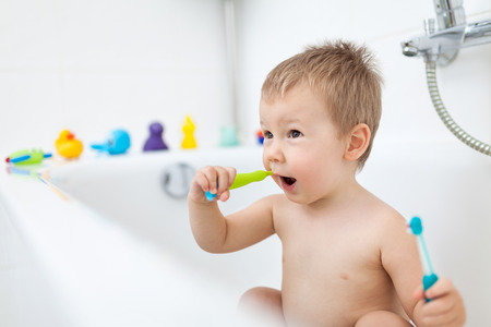 Adorable child learing how to brush his teeth in the bathroomの写真素材