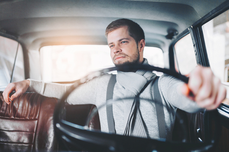 Handsome man sitting inside his old vintage carの写真素材