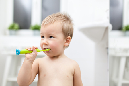 Adorable child learing how to brush his teeth in the bathroomの写真素材