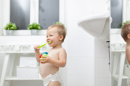 Adorable child learing how to brush his teeth in the bathroomの写真素材