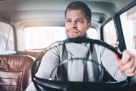 Handsome man sitting inside his old vintage carの写真素材