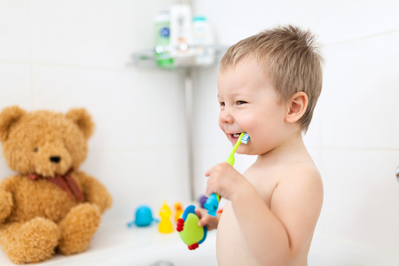 Adorable child learing how to brush his teeth in the bathroomの写真素材