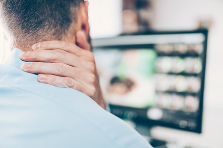 Office worker with neck and back pain from sitting at desk all dayの写真素材