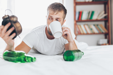 Young handsome man in bed the morning after night out drinkingの写真素材