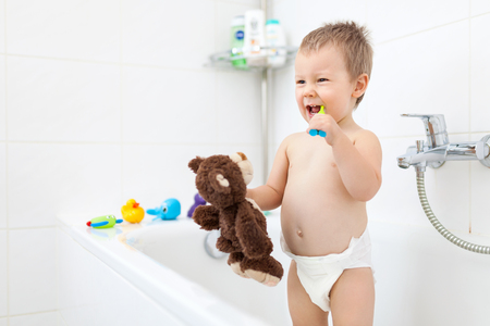 Adorable child learing how to brush his teeth in the bathroomの写真素材