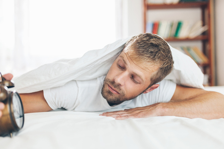 Young man finding it difficult to wake up in the morningの写真素材