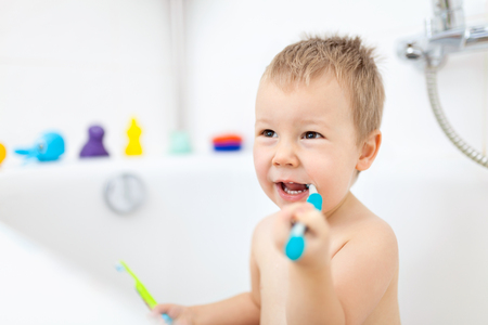 Adorable child learing how to brush his teeth in the bathroomの写真素材