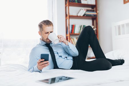 Young businessman working from a hotel room with his mobile phoneの写真素材