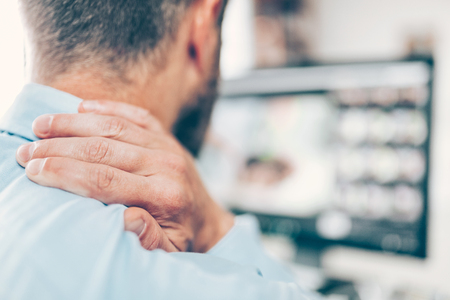Office worker with neck and back pain from sitting at desk all dayの写真素材
