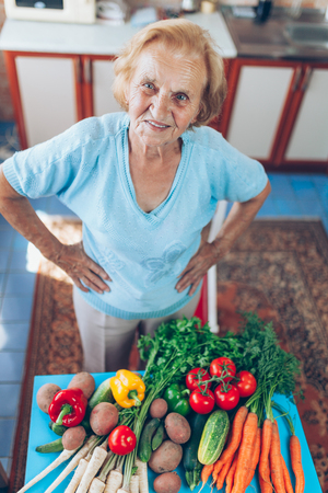 Happy senior woman at home with fresh crop from her gardenの写真素材