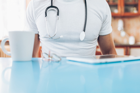 Doctor in his practice working with a digital tabletの写真素材