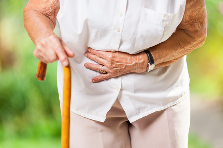 Elderly woman in the 80s with a walking stick and stomach painの写真素材