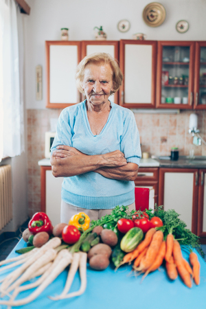 Happy senior woman at home with fresh crop from her gardenの写真素材