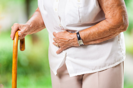 Elderly woman in the 80s with a walking stick and stomach painの写真素材