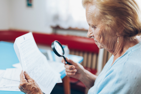 Elderly woman looking at her utility bills and paperworkの写真素材