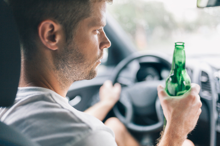 Drunk driver drinking behind the steering wheel of a carの写真素材
