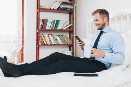 Young businessman working from a hotel room with his mobile phoneの写真素材