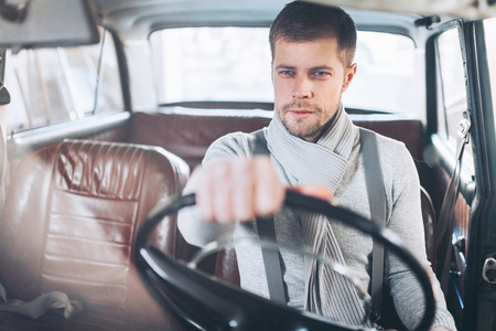 Handsome man sitting inside his old vintage carの写真素材