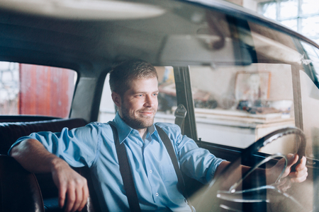Handsome man sitting inside his old vintage carの写真素材