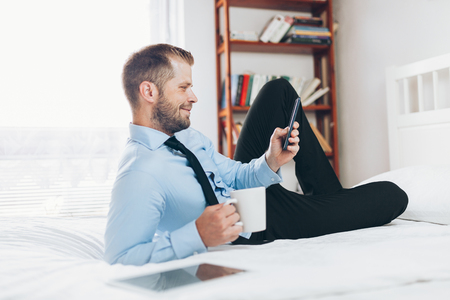 Young businessman working from a hotel room with his mobile phoneの写真素材