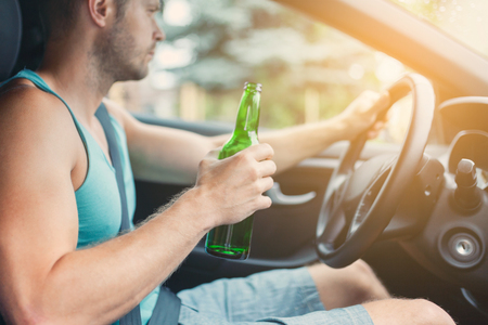 Drunk driver drinking behind the steering wheel of a car