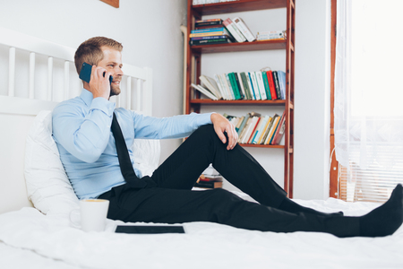 Young businessman working from a hotel room with his mobile phoneの写真素材