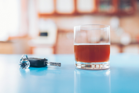 Drink driving. Car key and a glass of liquor on tableの写真素材