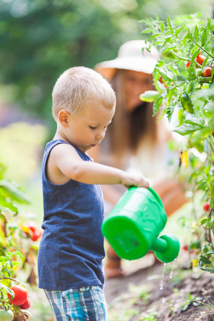 Cute toddler helphing out mom in the gardenの写真素材