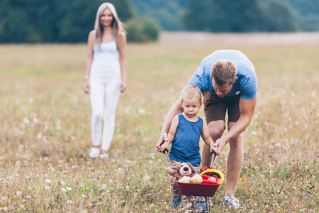 Adorable child with his parents pushing a whellbarrow outdoorsの写真素材
