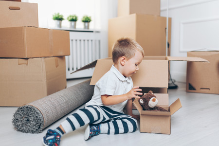Cute toddler helping out packing boxes and movingの写真素材