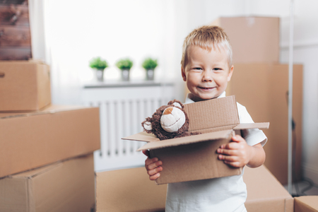 Cute toddler helping out packing boxes and movingの写真素材