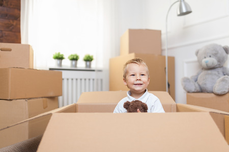 Cute toddler helping out packing boxes and movingの写真素材