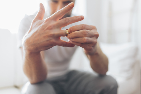 Heartbroken man at home holding a wedding ringの写真素材
