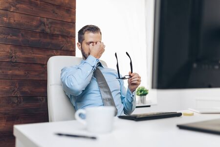 Tired businessman from heavy workload sitting at the deskの写真素材