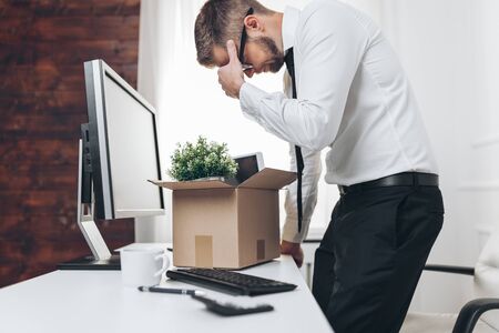 Dissapointed businessman clearing his desk after being made redundantの写真素材