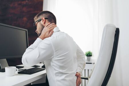 Office worker with back pain from sitting at desk all dayの写真素材