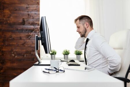 Office worker with back pain from sitting at desk all dayの写真素材