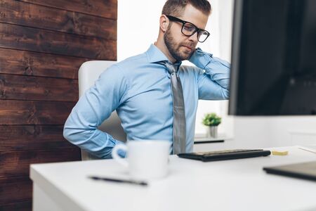 Office worker with back pain from sitting at desk all dayの写真素材