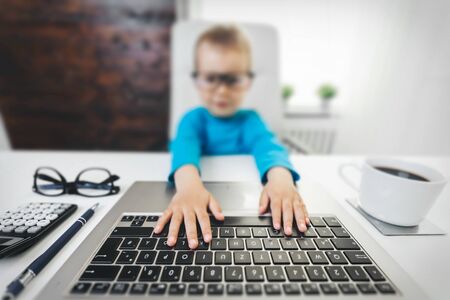 Cute child with glasses learning how to use a laptopの写真素材