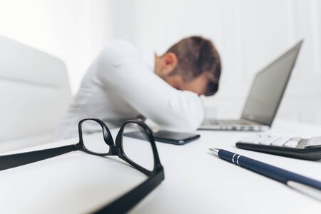 Tired businessman from heavy workload sitting at the deskの写真素材