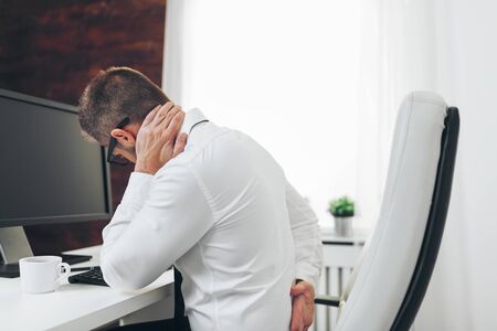 Office worker with back pain from sitting at desk all dayの写真素材