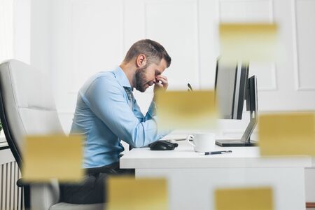 Tired businessman from heavy workload sitting at the deskの写真素材