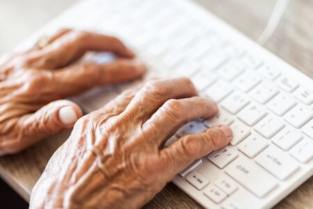 Elderly woman typing on a PC keyboardの写真素材
